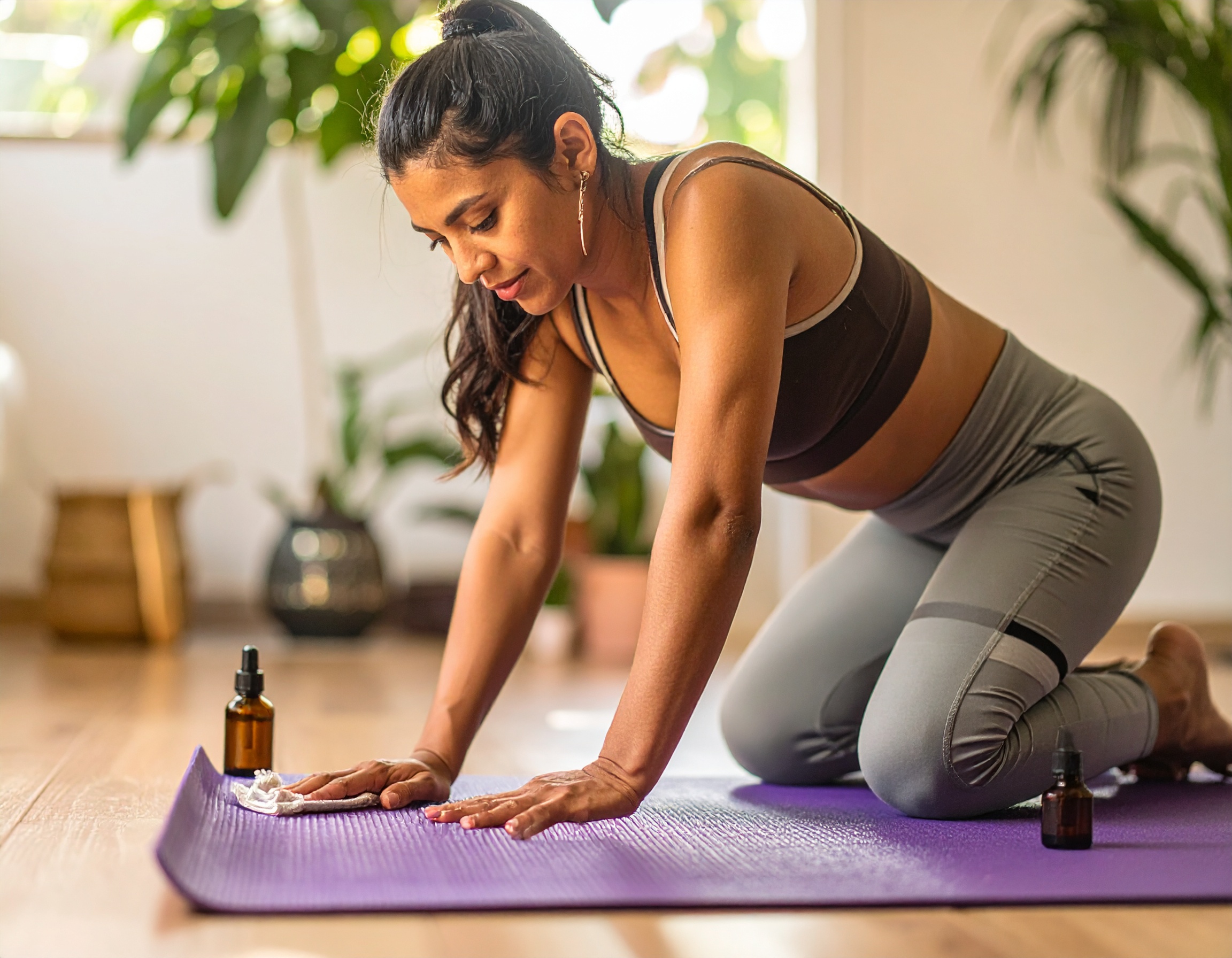une yogi qui nettoie son tapis de yoga avec des huiles essentielles